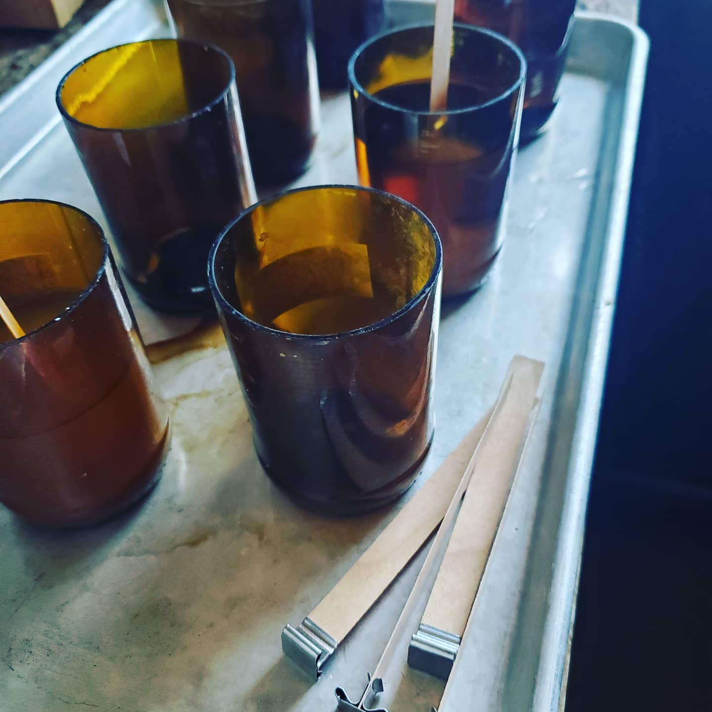A finished candle glowing in an amber recycled beer-bottle vessel