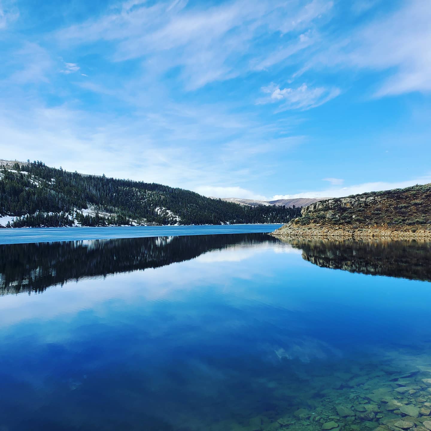 A mirror-still mountain lake under a wide Utah sky
